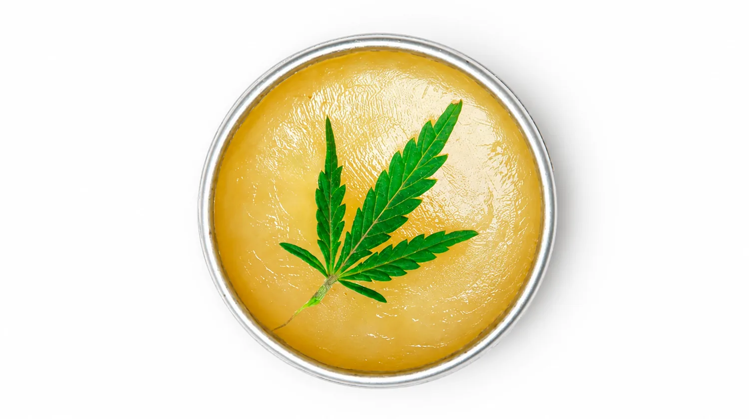 Mantequilla de cannabis casera y dorada en un tarro con una hoja de cannabis